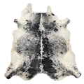 A natural black and white cowhide rug with a distinct spotted pattern and textured hide shape, shown flat against a solid white background.